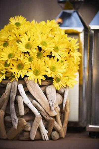 yellow daisies and drift wood collected in a glass vase make unique table centerpiece