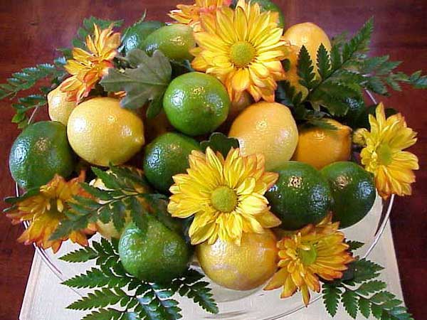 yellow mums and daisies with green leaves and citrus fruits are great centerpiece ideas