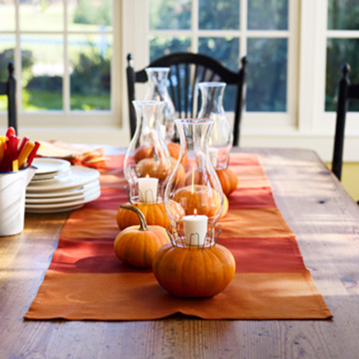 mini pumpkins with candles centerpieces on stripes yellow red table runner