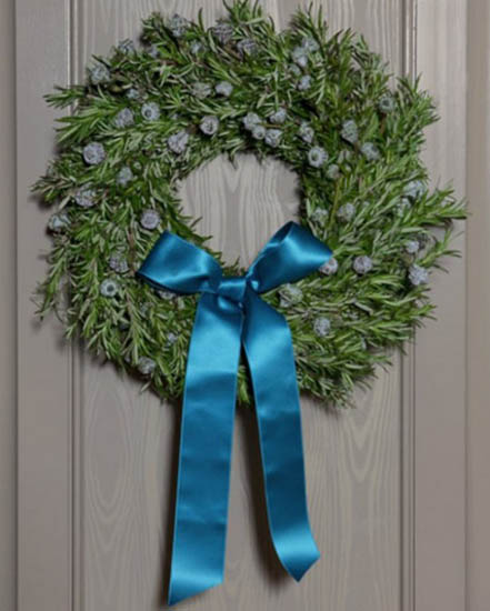 green Christmas wreath with a blue ribbon for wall decoration