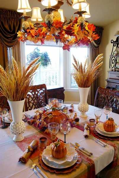 Wheat heads in white vases and candlesticks with autumn leaves decorated