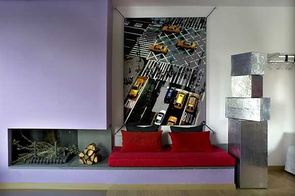 Living room design with inglenook fireplace, steel sculpture, red sofa and large work of art