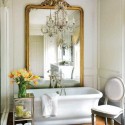 golden large wall mirror and white tub with yellow flowers in modern bathroom