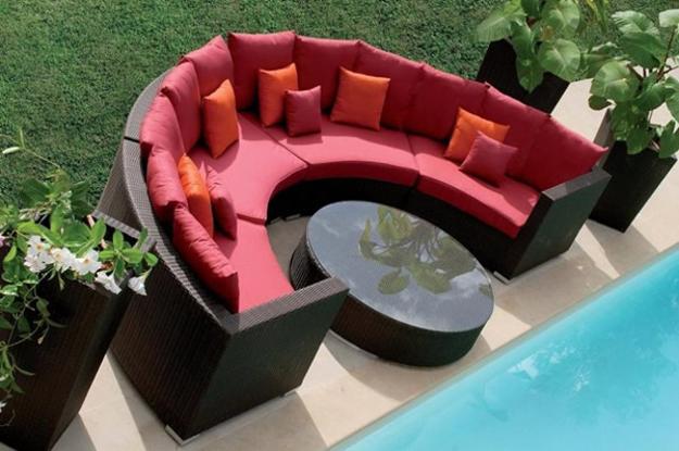 round coffee table and outdoor sofa with red pillows